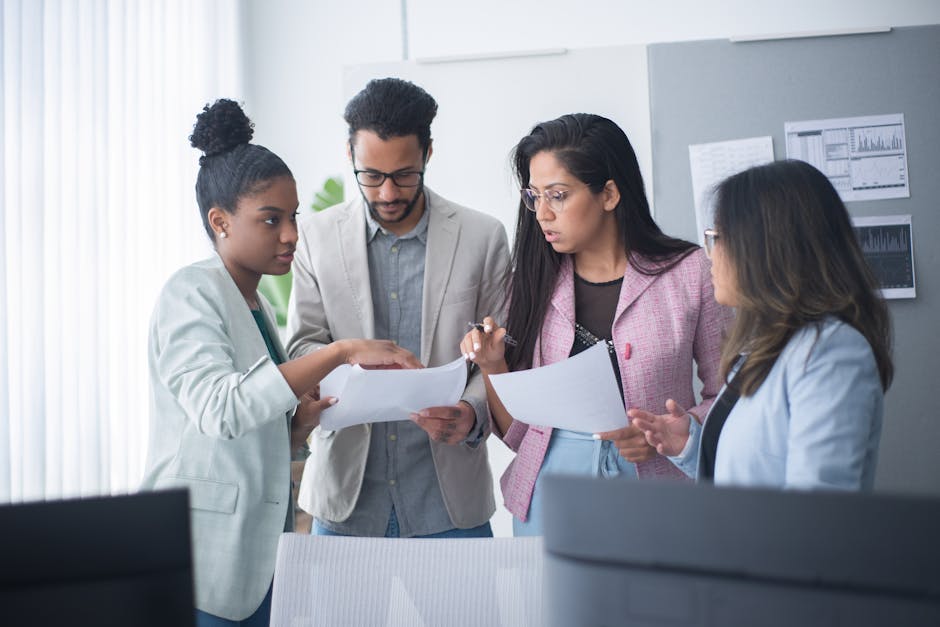 A diverse group of professionals engaged in a focused team meeting within an office environment.